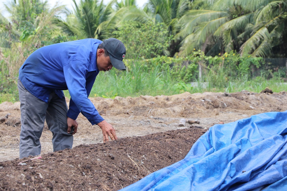 Mr. Thanh, a farmer-partner, examines the output of the rice straw compost turner. (Photo by R. Quilloy)